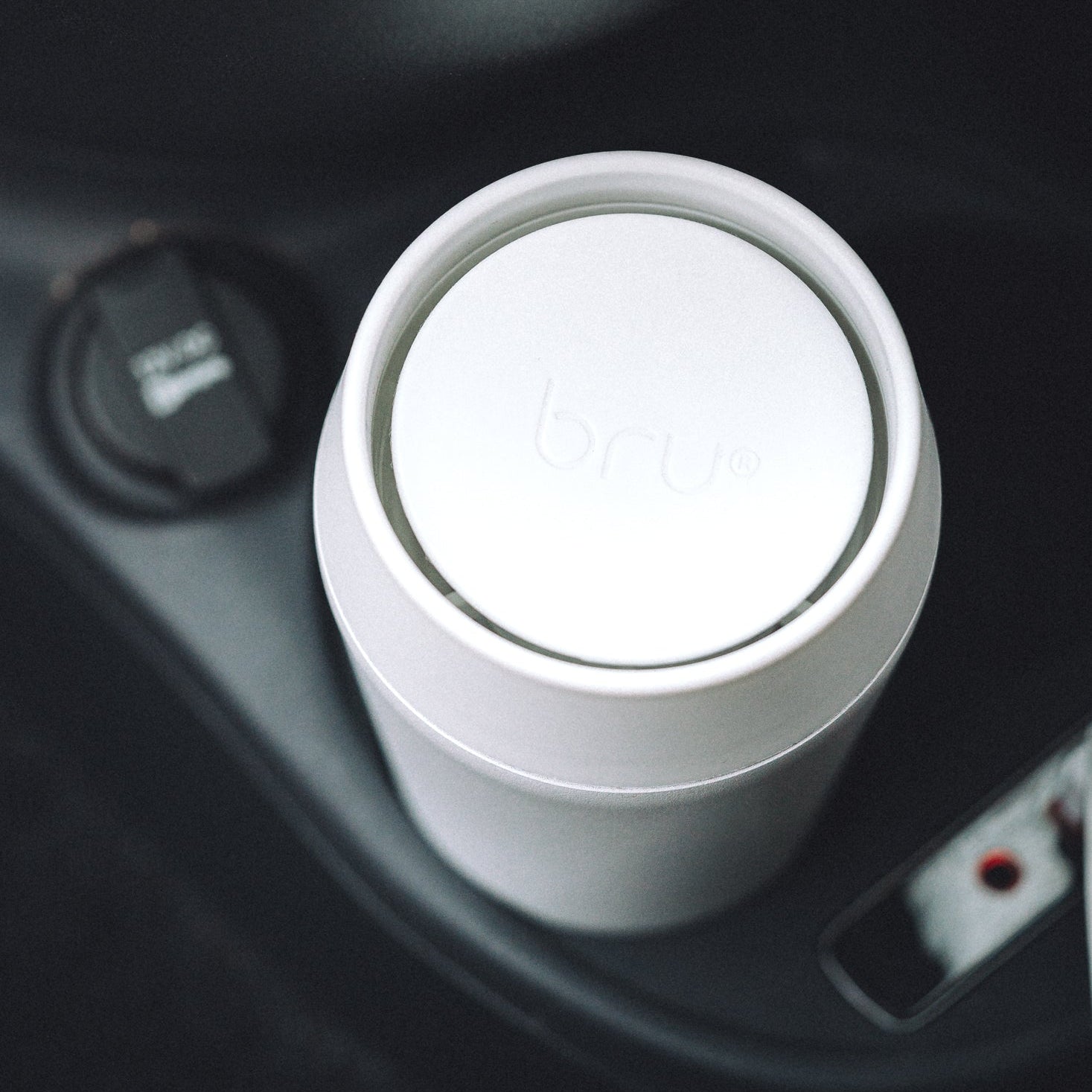 bru white insulated travel mug in a car cup holder, viewed from above
