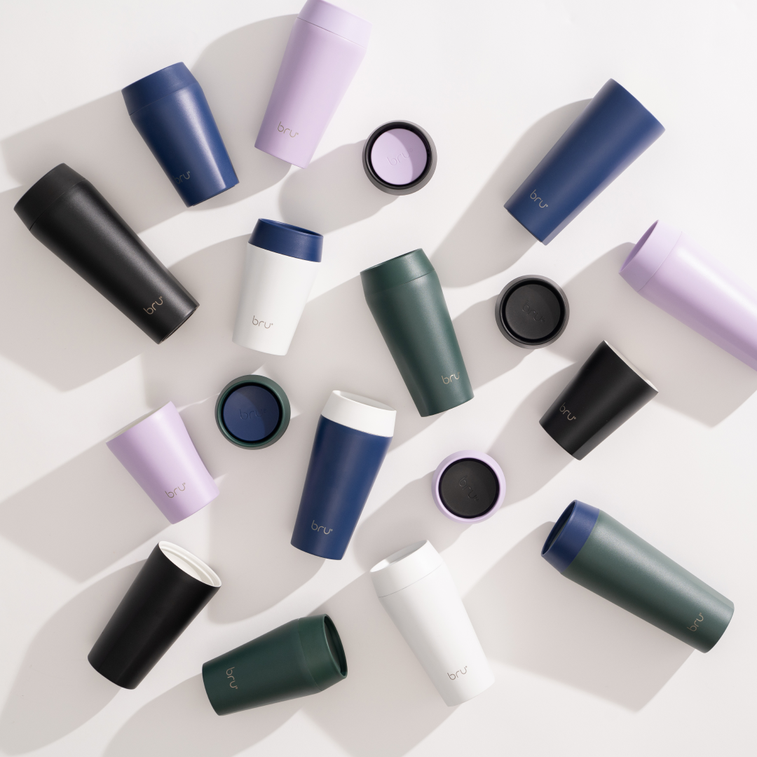flatlay of the full bru insulated travel mug range in black, white, navy, lilac and dark green with lids off

